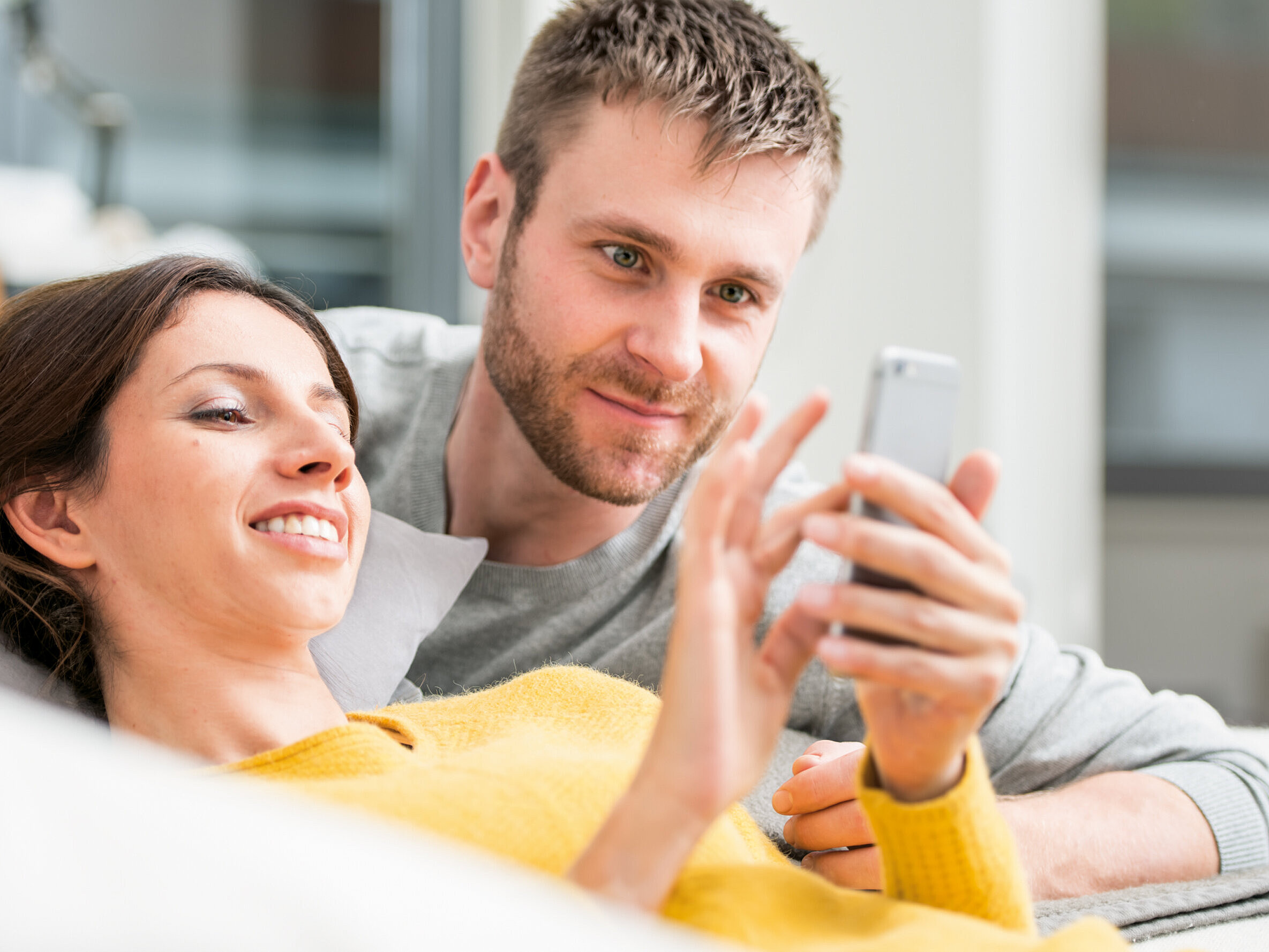 femme allongée sur le canapé regarde le smartphone
